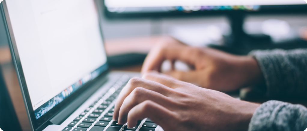 Hands typing on a laptop