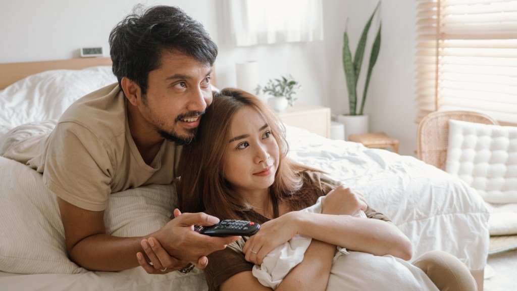 Asian couple watches TV