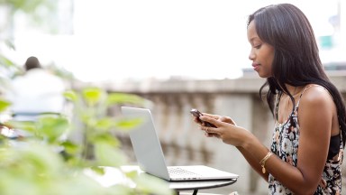 Woman using phone while sitting at sidewalk cafe